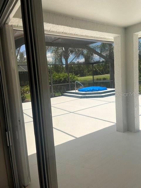 A view from a covered patio looking out toward a screened pool deck and pond — 8144 SANGUINELLI ROAD, LAND O LAKES, FL