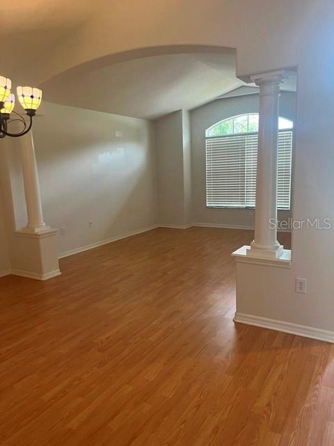 An empty room features light wood flooring, an arched entryway, and two decorative white columns — 8144 SANGUINELLI ROAD, LAND O LAKES, FL