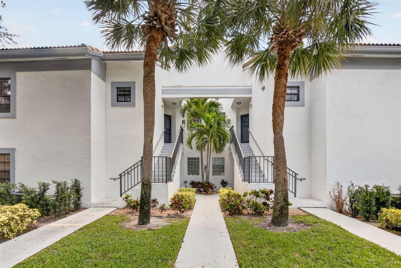 A two-story white apartment building features symmetrical outdoor staircases and two tall palm trees — 5418 Firenze Drive # F, Boynton Beach FL 33437, BOYNTON BEACH, FL