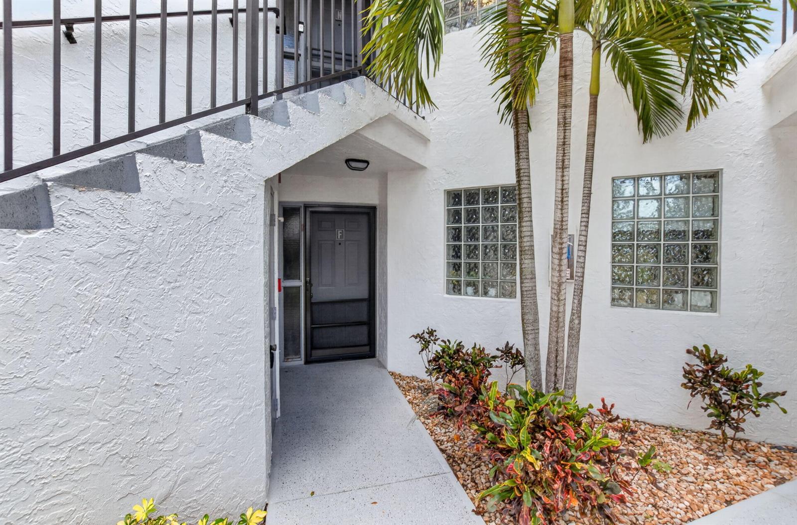 The exterior view shows a white stucco building entrance with stairs, palm trees, and landscaping — 5418 Firenze Drive # F, Boynton Beach FL 33437, BOYNTON BEACH, FL