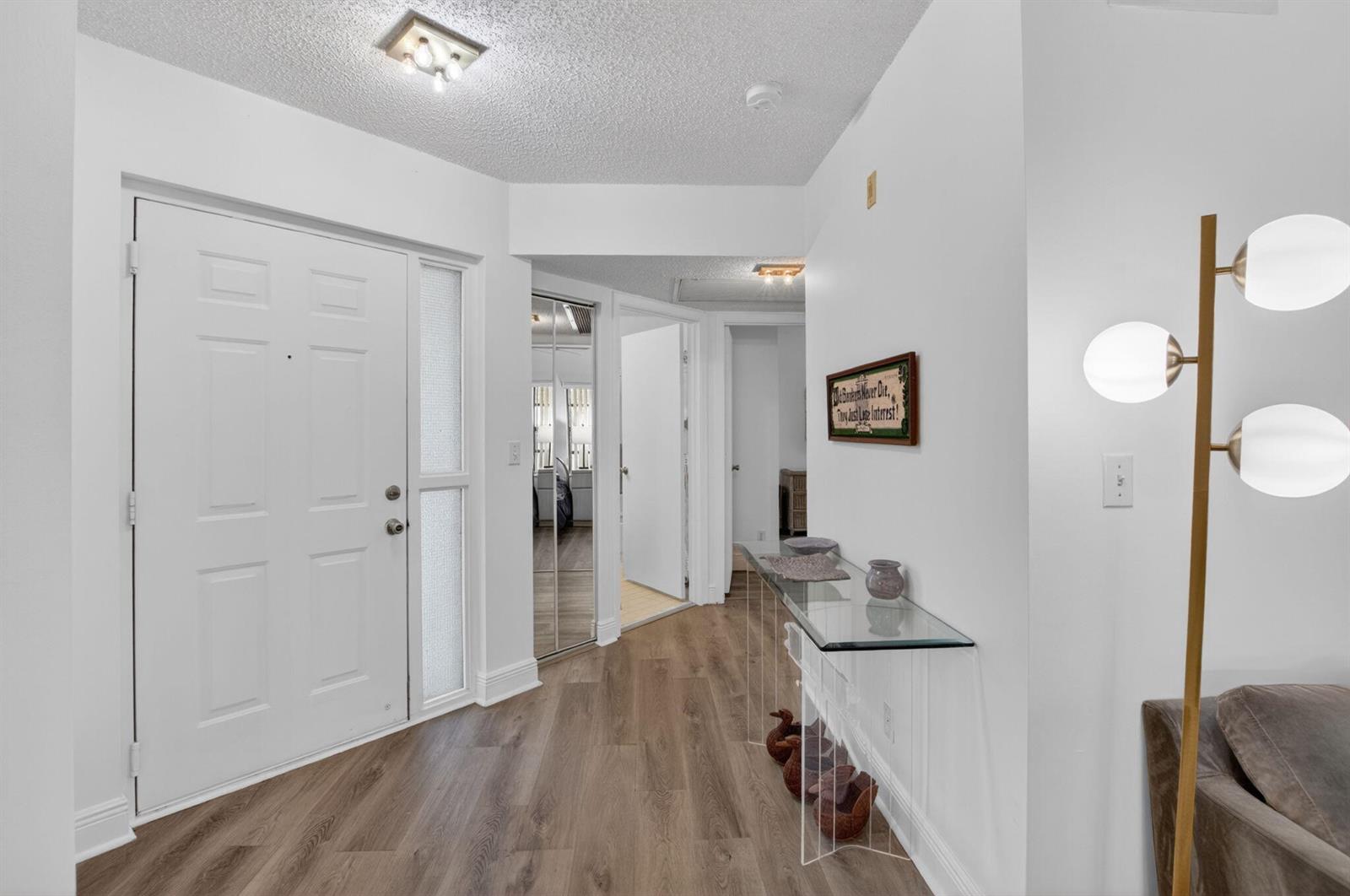 An entryway features wood-look flooring, a white front door with a sidelight, and a glass console table — 5418 Firenze Drive # F, Boynton Beach FL 33437, BOYNTON BEACH, FL