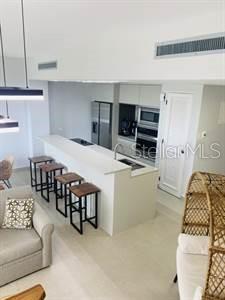 A modern kitchen features a white island with four bar stools and stainless steel appliances — LAS CASITAS VILLAGE 1 AVE CONQUISTADOR UNIT 5392, FAJARDO, PR