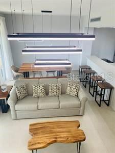 A living room with a beige sofa, a live-edge coffee table, and modern pendant lighting — LAS CASITAS VILLAGE 1 AVE CONQUISTADOR UNIT 5392, FAJARDO, PR