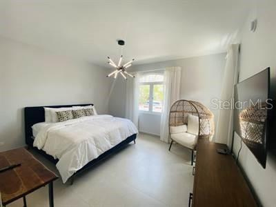 A bedroom features a dark bed frame, a rattan egg chair, and a modern light fixture — LAS CASITAS VILLAGE 1 AVE CONQUISTADOR UNIT 5392, FAJARDO, PR