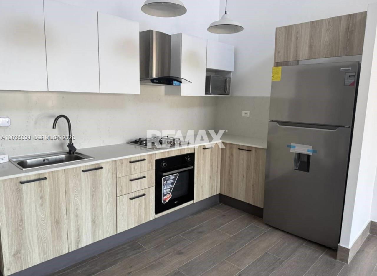 A modern kitchen features light wood cabinets, white upper cabinets, stainless steel appliances, and countertops — fh9m Cap Cana # 515, 1 1, 1