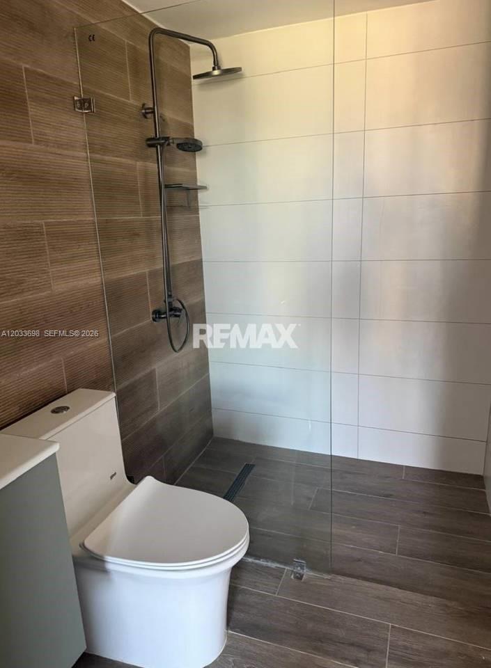 A modern bathroom features a glass-enclosed walk-in shower with wood-look tile and a toilet — fh9m Cap Cana # 515, 1 1, 1