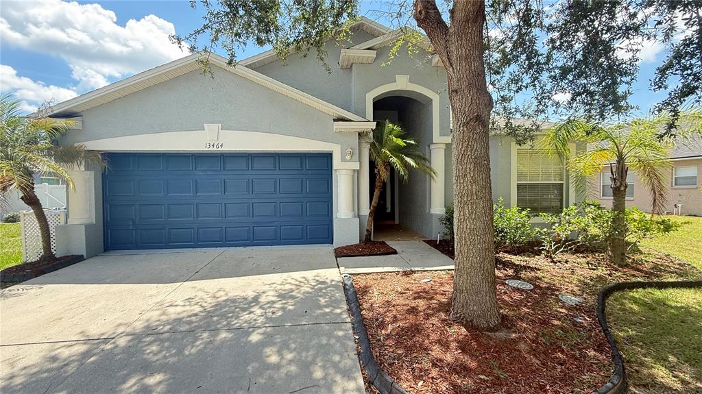 A single-story house with a blue garage door, gray stucco siding, and a front walkway — 13464 FLADGATE MARK DRIVE, RIVERVIEW, FL