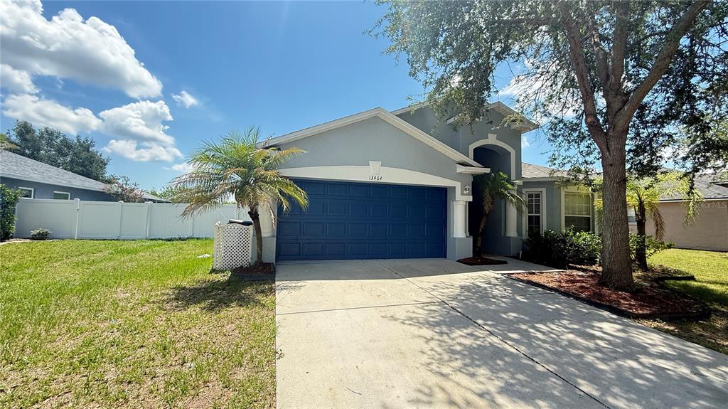 A single-story house with a blue garage door, a palm tree, and a concrete driveway — 13464 FLADGATE MARK DRIVE, RIVERVIEW, FL