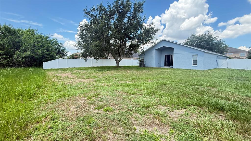 A blue house with a large tree and white vinyl fencing in the backyard — 13464 FLADGATE MARK DRIVE, RIVERVIEW, FL