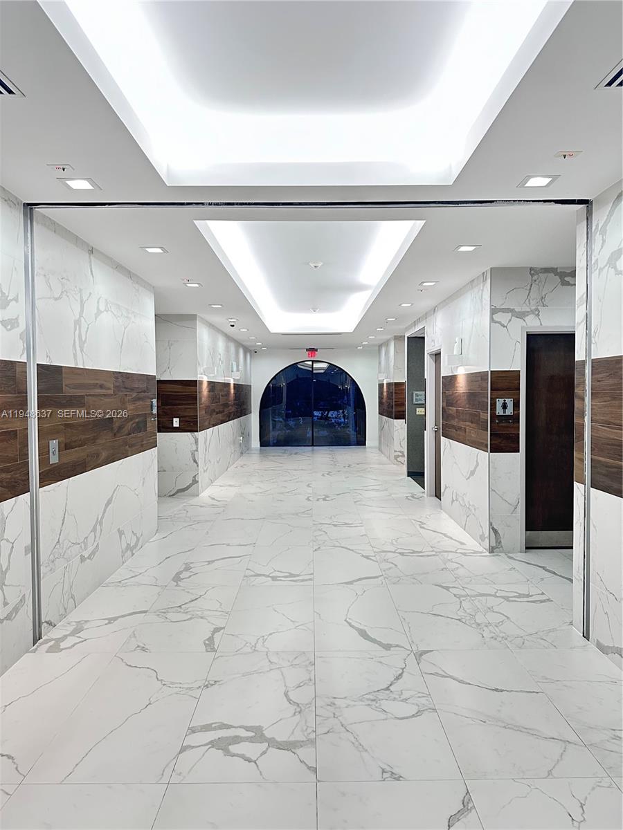 A modern hallway features white marble-patterned tile, wood-paneled walls, and a recessed ceiling light — 14261 Commerce Way, Miami Lakes FL 33016, MIAMI LAKES, FL