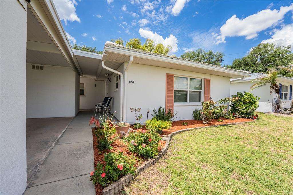 A single-story white house with green shutters, a carport, and a palm tree in front — 652 COTTAGE LANE, LAKELAND, FL