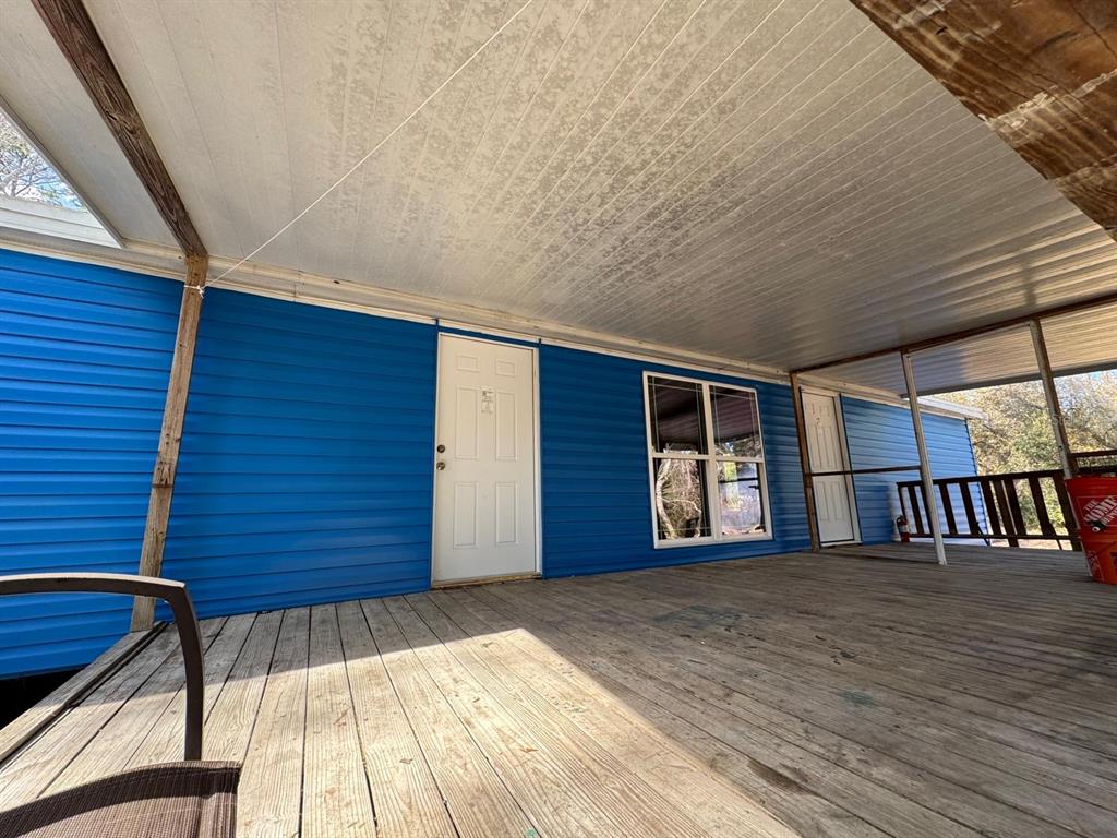 A wooden deck leads to a blue-sided home with a white door and window — 13395 NE 65TH COURT, CITRA, FL