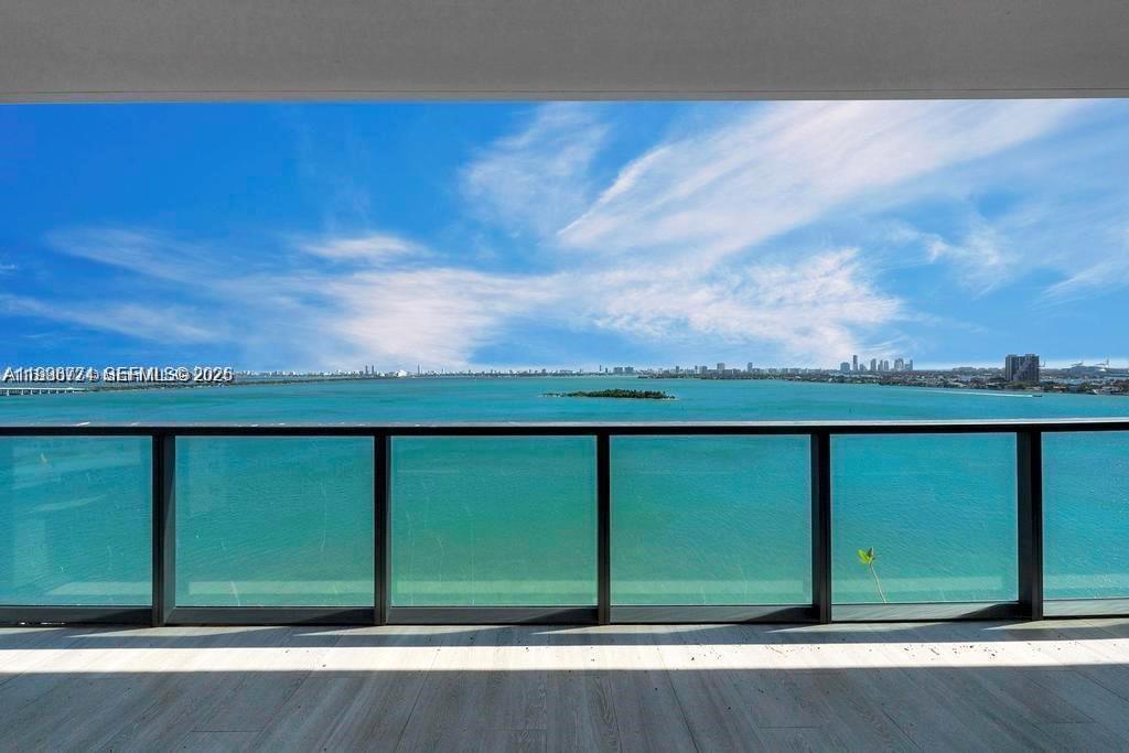 A balcony with a glass railing overlooks a wide bay and a distant city skyline — 788 NE 23rd St # 1402, Miami FL 33137, MIAMI, FL