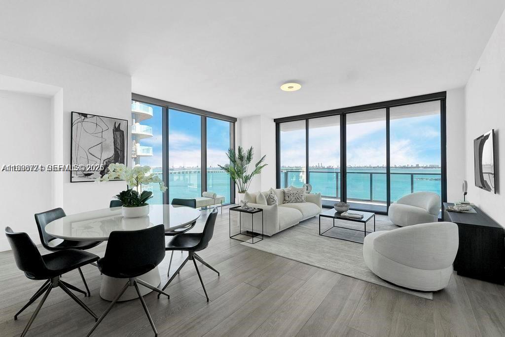 A modern living and dining area features floor-to-ceiling windows with a view of the water — 788 NE 23rd St # 1402, Miami FL 33137, MIAMI, FL