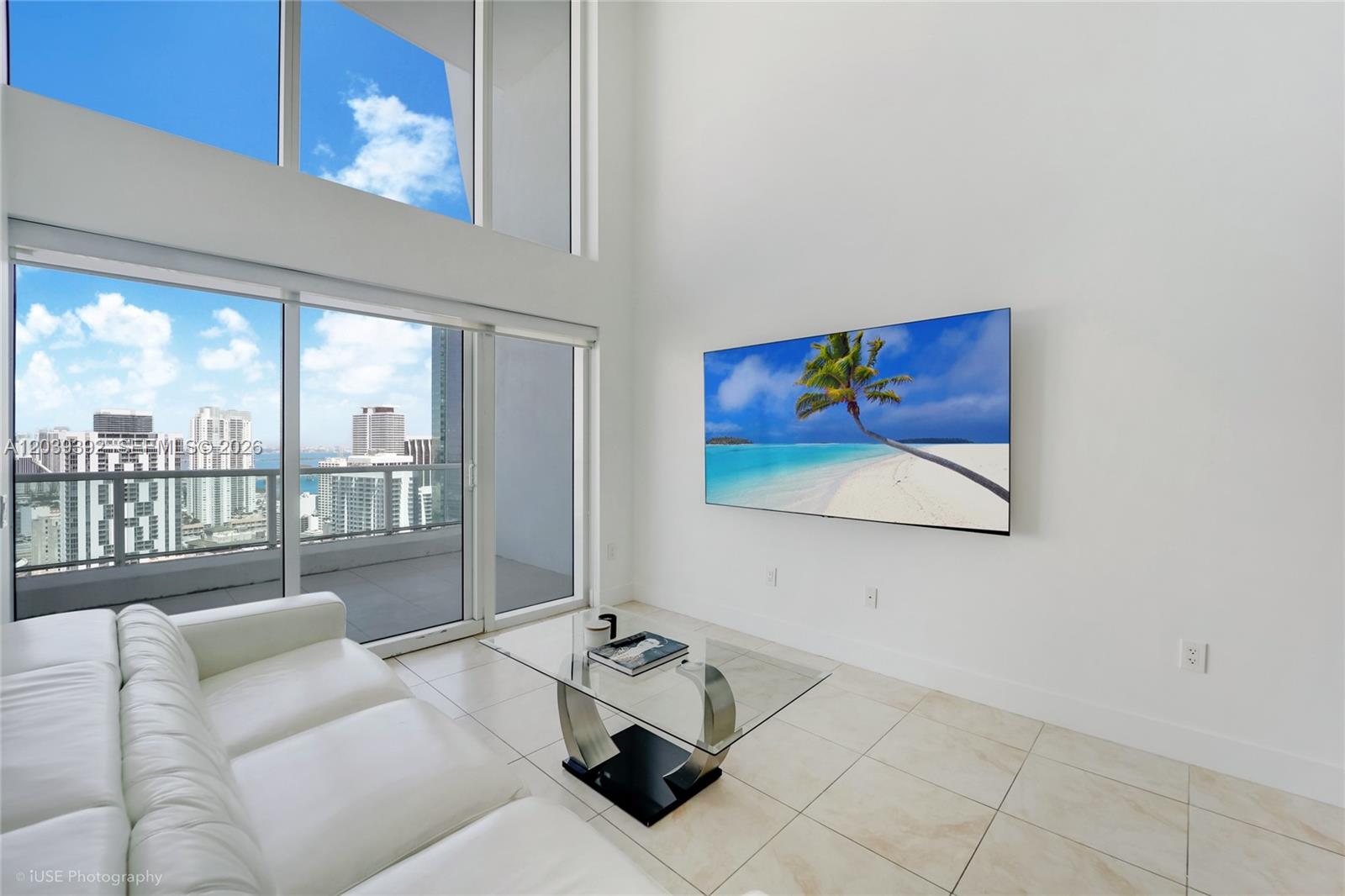 A modern living room features a white sofa, glass coffee table, and a wall-mounted television — 41 SE 5th St # 2409, Miami FL 33131, MIAMI, FL