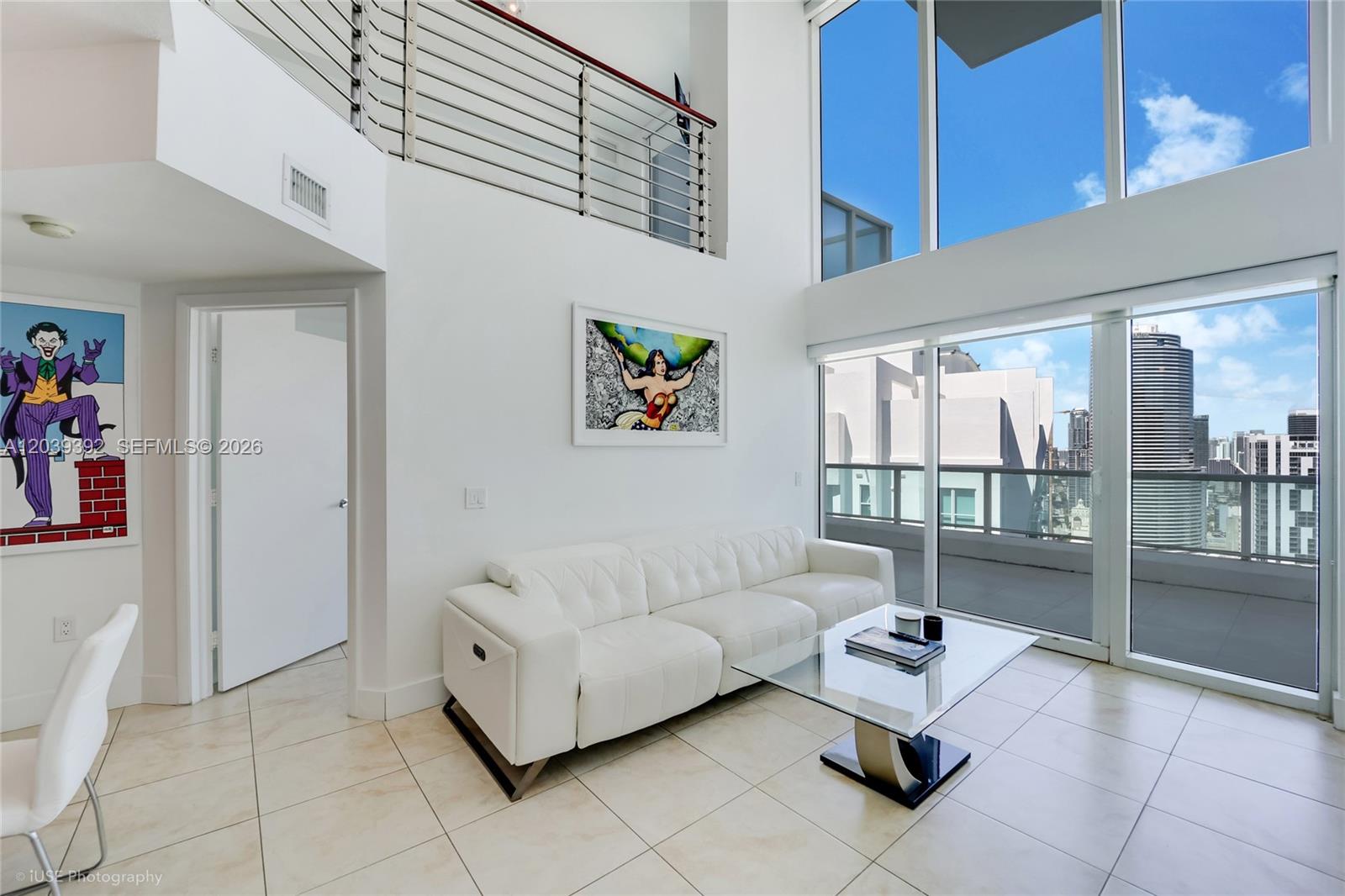 A modern living room features a white leather sofa, glass coffee table, and floor-to-ceiling windows — 41 SE 5th St # 2409, Miami FL 33131, MIAMI, FL