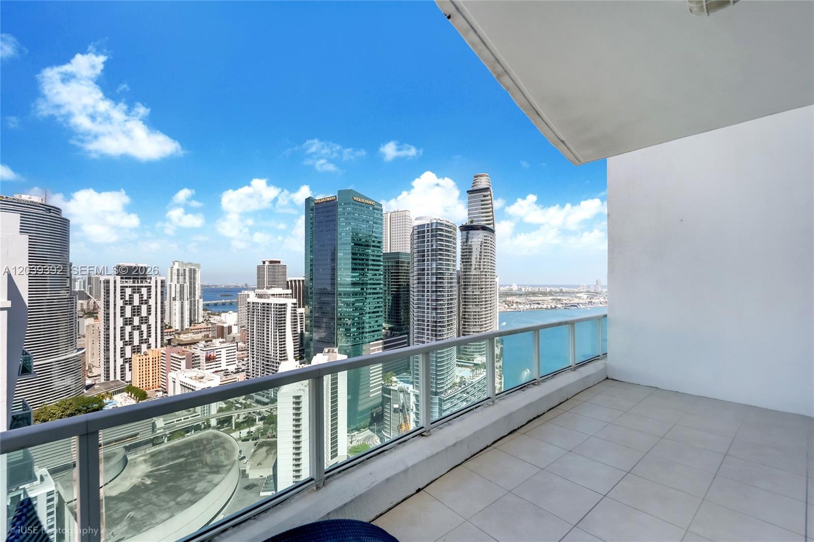 A balcony with tiled flooring overlooks a dense city skyline and a body of water — 41 SE 5th St # 2409, Miami FL 33131, MIAMI, FL