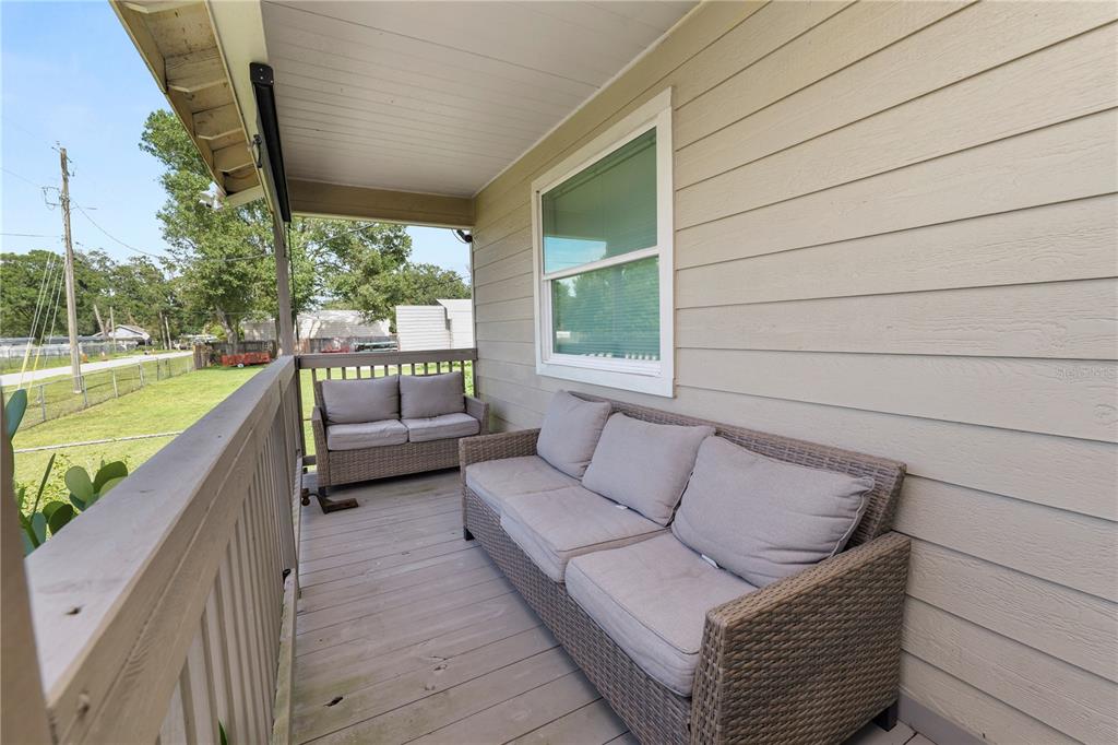 A covered wooden porch features two wicker sofas with gray cushions and beige siding — 2001 W BALL STREET, PLANT CITY, FL