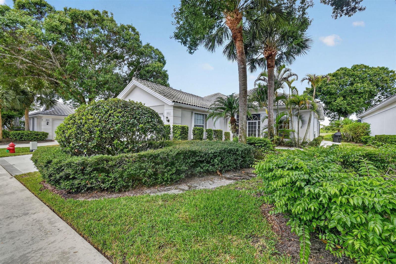 A single-story house with a tiled roof, palm trees, and manicured landscaping in the front yard — 8081 SE Double Tree Drive, Hobe Sound FL 33455, HOBE SOUND, FL