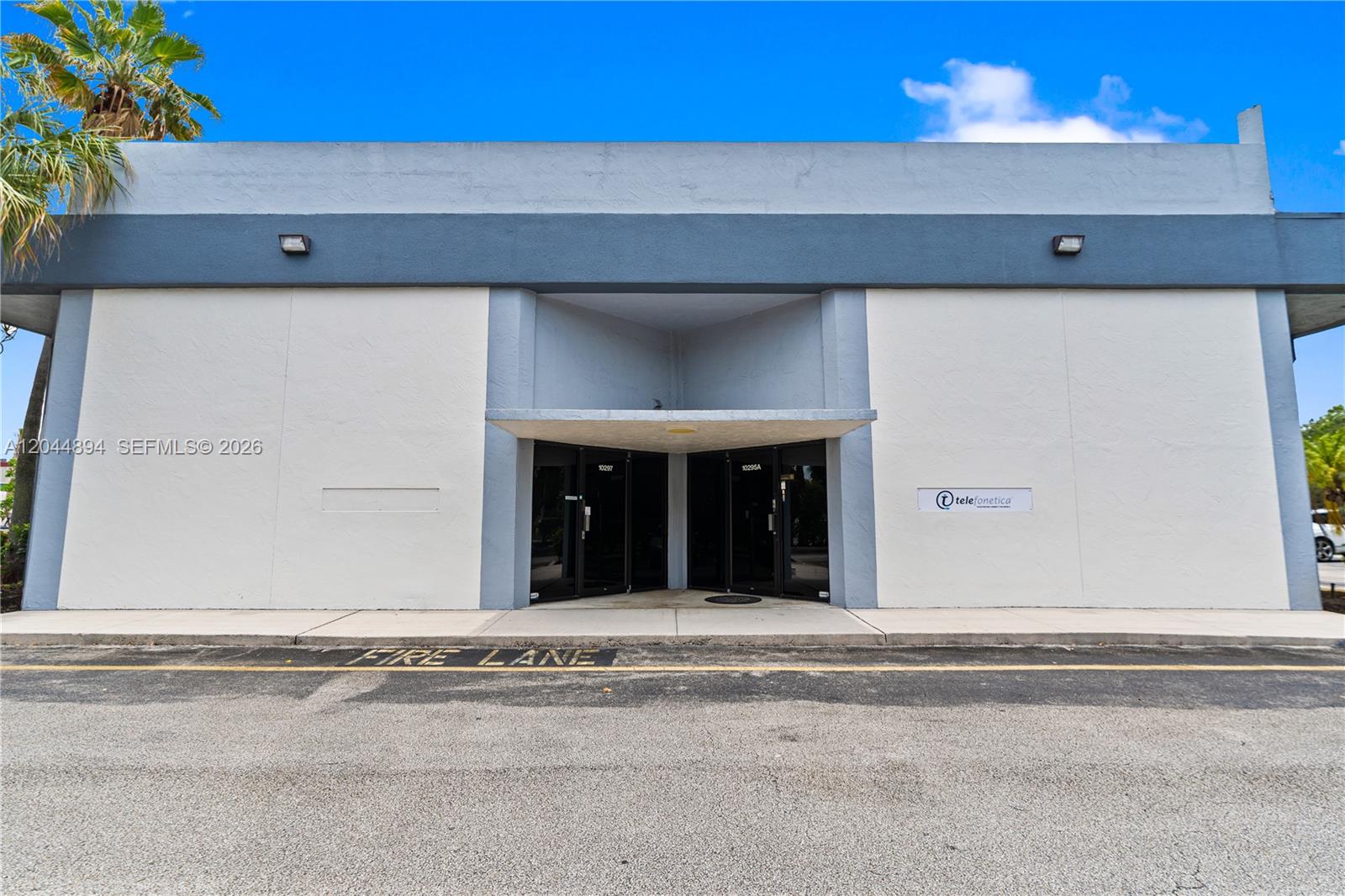 The exterior of a commercial building features a recessed entrance with glass doors and signage — 10297 NW 46th St # 1A, Sunrise FL 33351, SUNRISE, FL