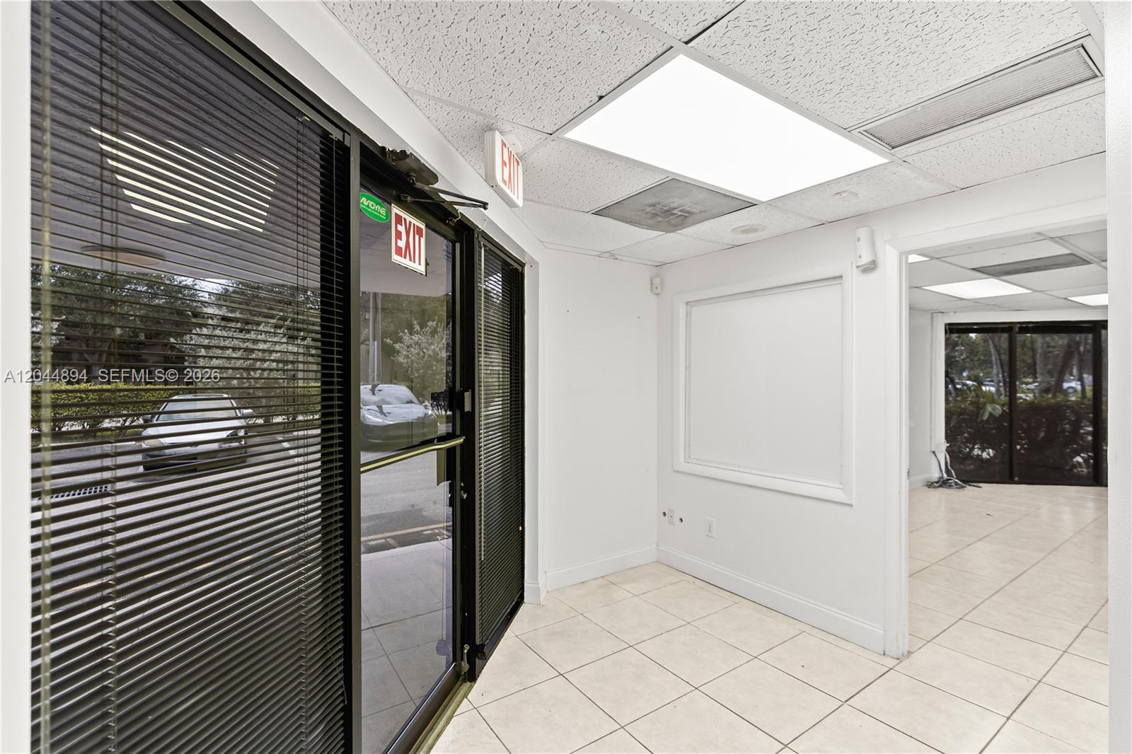 An office interior features tiled floors, a glass entrance door, and a white wall panel — 10297 NW 46th St # 1A, Sunrise FL 33351, SUNRISE, FL