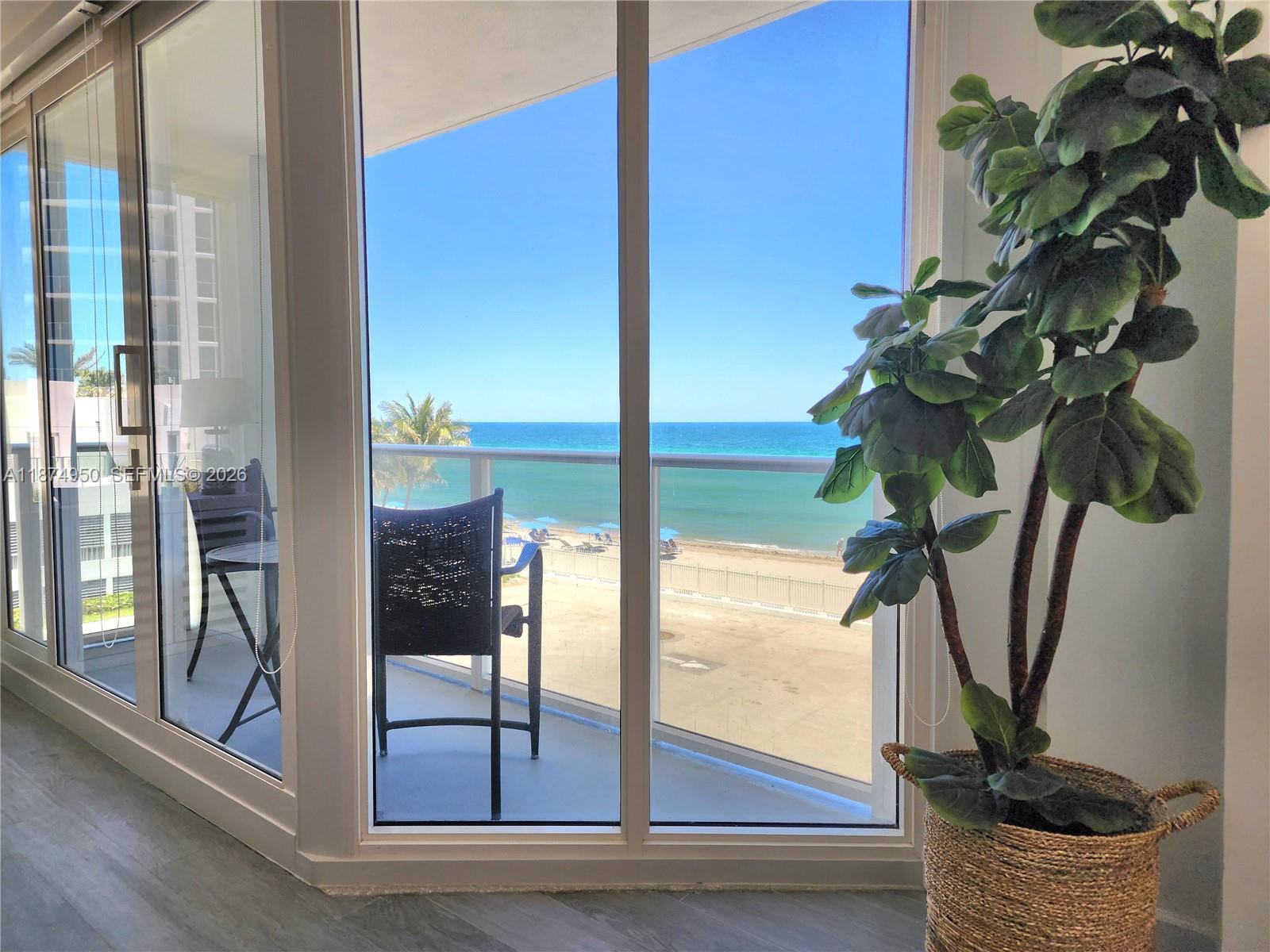 A view of the ocean and beach from a balcony through large glass sliding doors — 3505 S Ocean Dr # 312, Hollywood FL 33019, HOLLYWOOD, FL