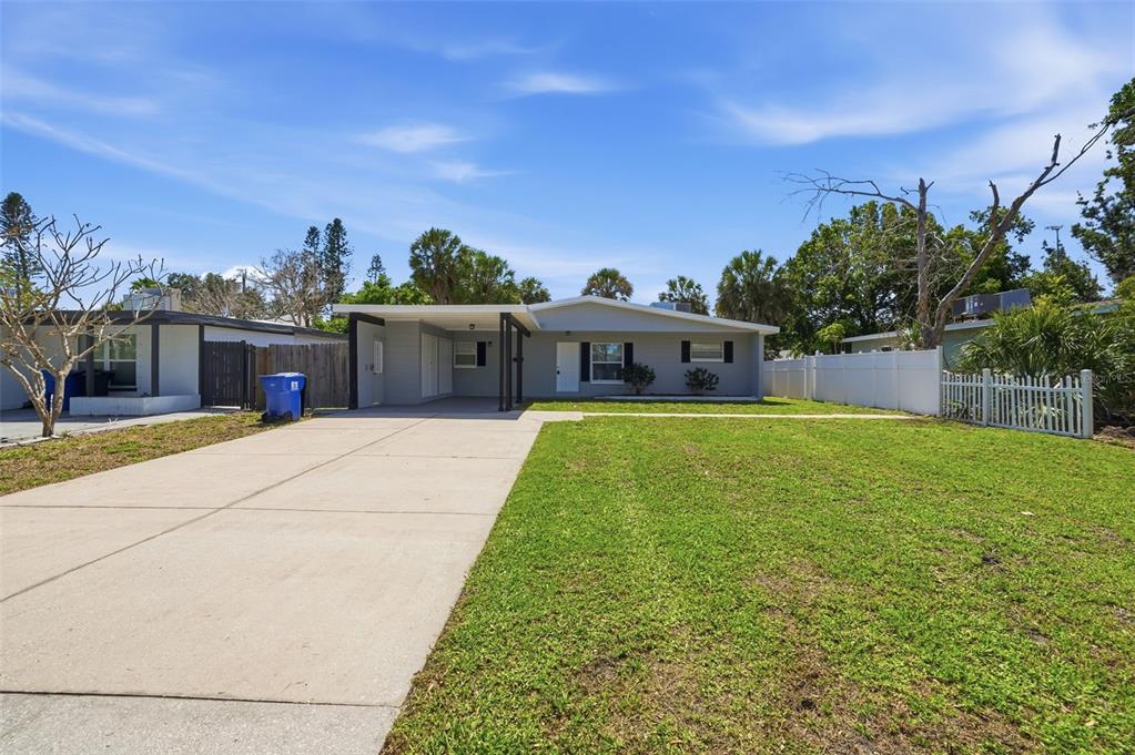 A single-story house with a concrete driveway, carport, and a large front lawn — 3934 HELENA STREET NE, ST PETERSBURG, FL