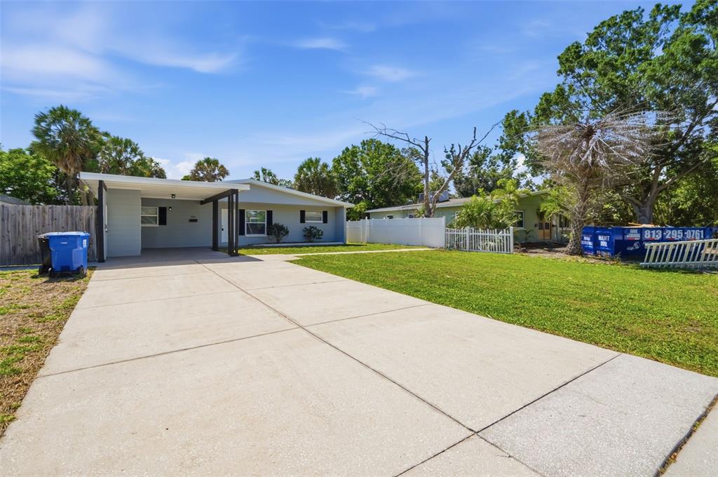A light-colored single-story house with a carport and a concrete driveway under a blue sky — 3934 HELENA STREET NE, ST PETERSBURG, FL