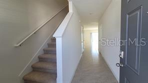 An entryway with a carpeted staircase on the left and a tiled hallway leading forward — 1215 DRAINTREE STREET, DAVENPORT, FL