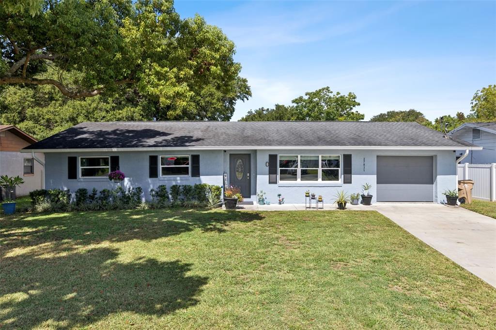 A single-story light blue house with a dark roof, a front lawn, and a garage — 27821 LOIS DRIVE, TAVARES, FL