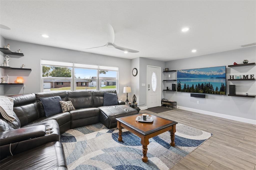A living room features a large sectional sofa, a coffee table, and a wall-mounted television — 27821 LOIS DRIVE, TAVARES, FL