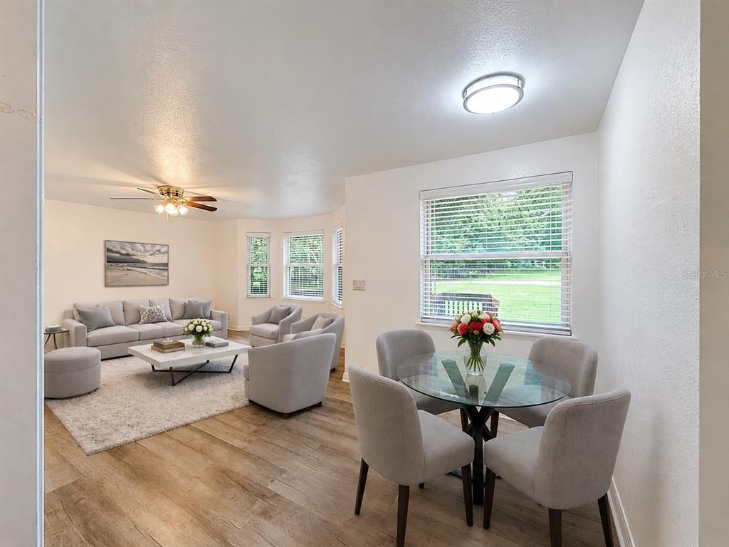 A living room and dining area feature light wood floors, neutral furniture, and large windows — 1926 MEADOWRIDGE DRIVE, VALRICO, FL