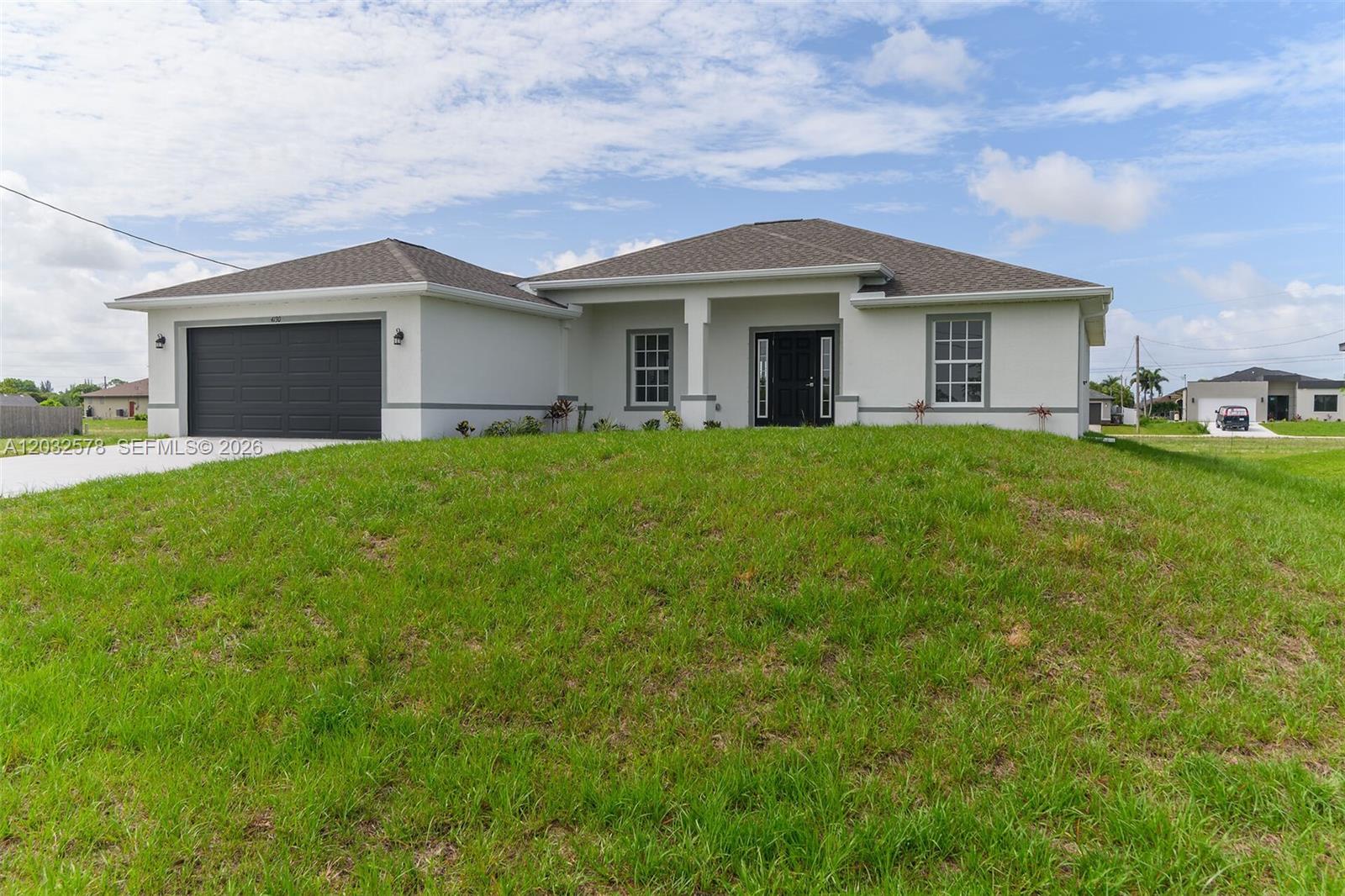 A single-story house with a white stucco exterior, dark garage door, and a grassy yard — 4130 NW 33rd, Cape Coral FL 33993, CAPE CORAL, FL