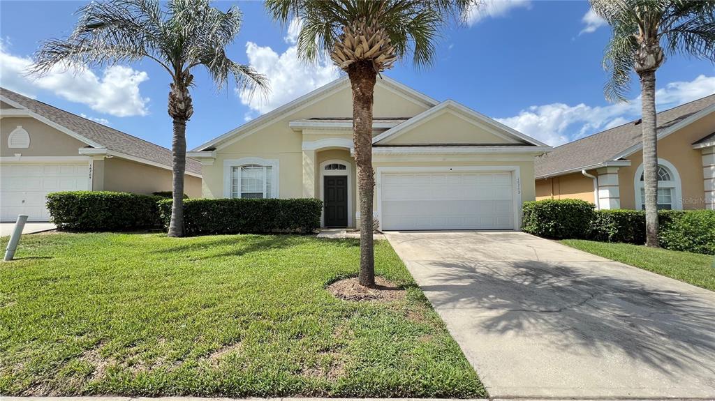 A single-story house with a beige exterior, a two-car garage, and two palm trees — 16709 FRESH MEADOW DRIVE, CLERMONT, FL
