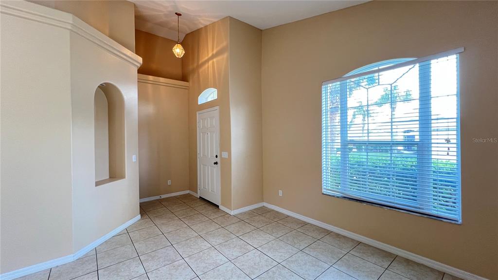 An entryway with tile flooring, a high ceiling, and a large window with blinds — 16709 FRESH MEADOW DRIVE, CLERMONT, FL