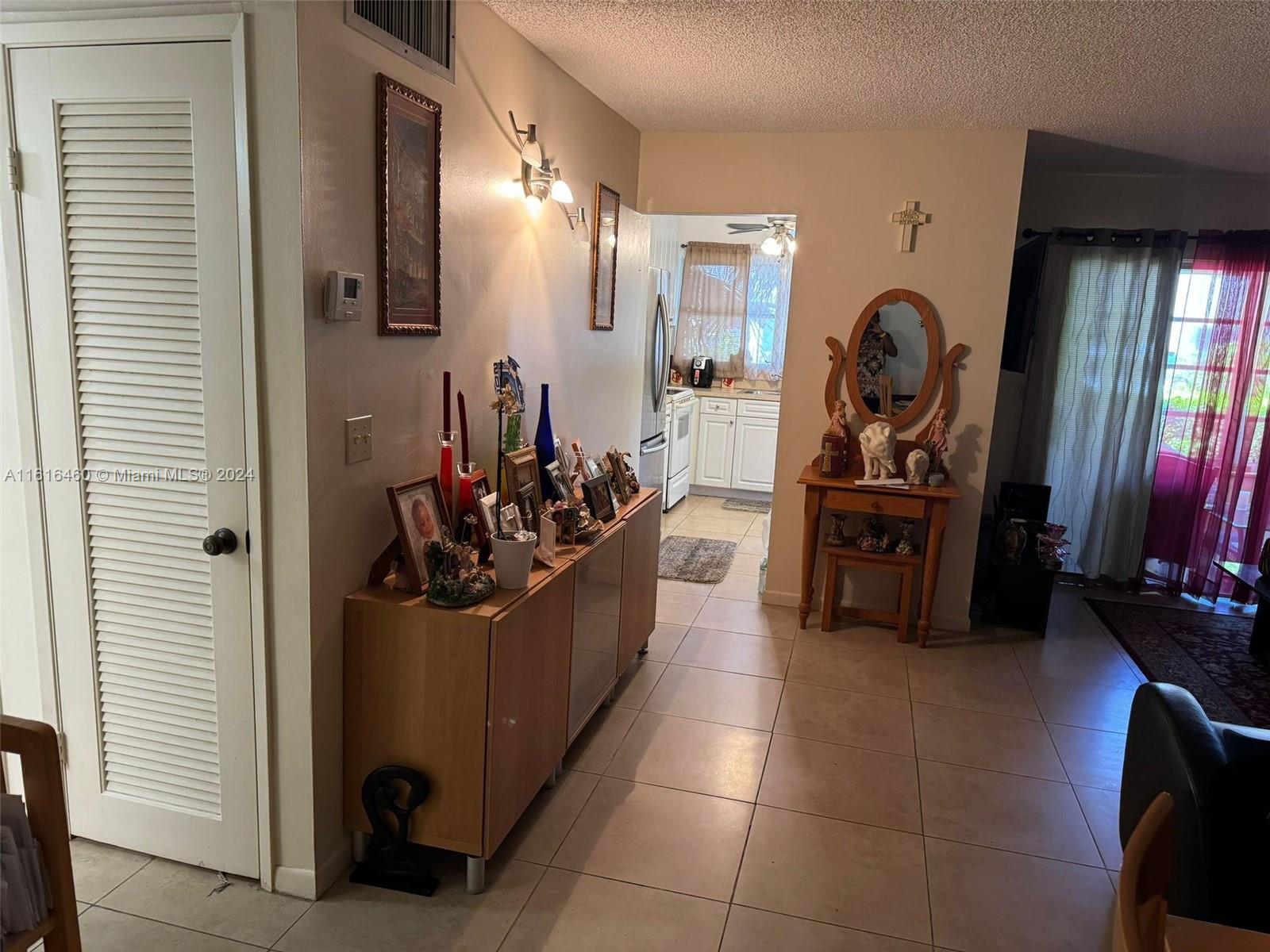 A hallway with tile floors leads to a kitchen, featuring a console table and vanity — 4047 NW 16th St # 110, Lauderhill FL 33313, LAUDERHILL, FL