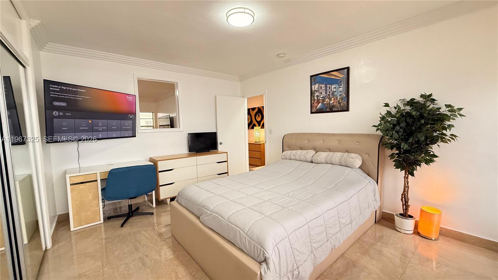 A bedroom features a bed, a desk, a dresser, a television, and a potted plant — 650 Pennsylvania Ave # 2, Miami Beach FL 33139, MIAMI BEACH, FL