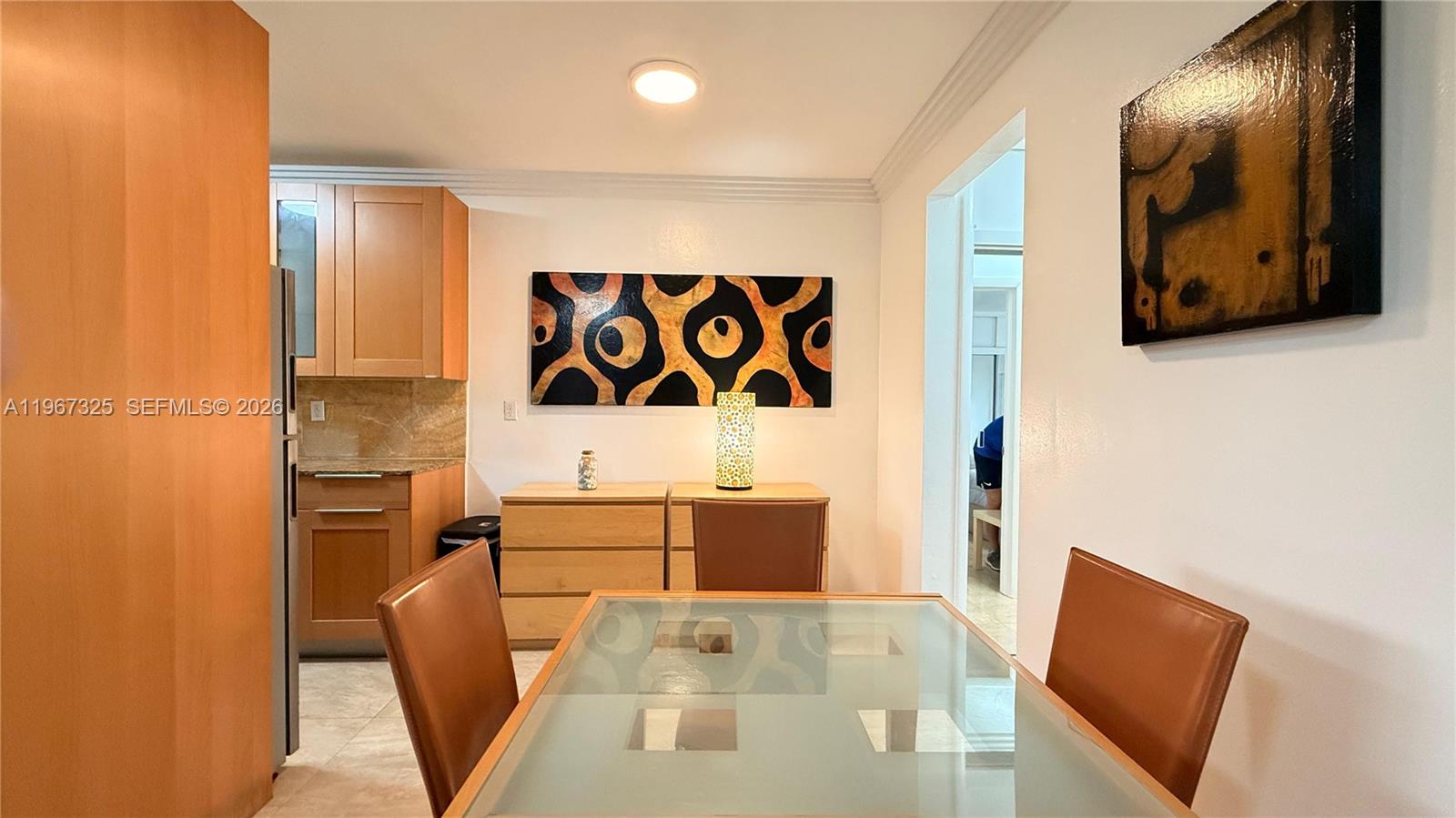 A dining area features a glass-topped table, wooden cabinets, and two abstract wall paintings — 650 Pennsylvania Ave # 2, Miami Beach FL 33139, MIAMI BEACH, FL