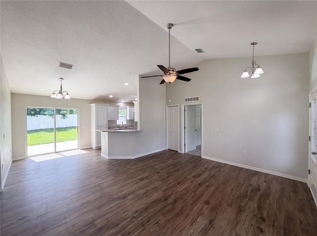 An open-concept living and dining area features wood-look flooring, a ceiling fan, and sliding doors — 5434 PARNELL AVENUE, SPRING HILL, FL