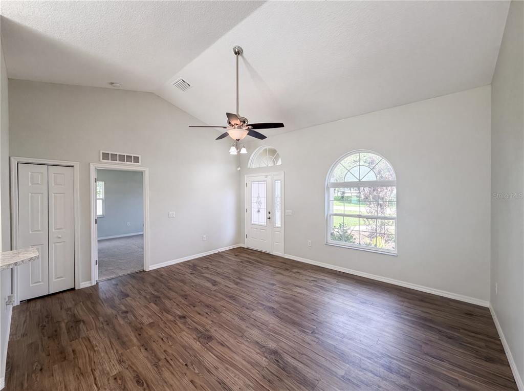 A living room with vaulted ceilings, wood-look flooring, a ceiling fan, and an arched window — 5434 PARNELL AVENUE, SPRING HILL, FL
