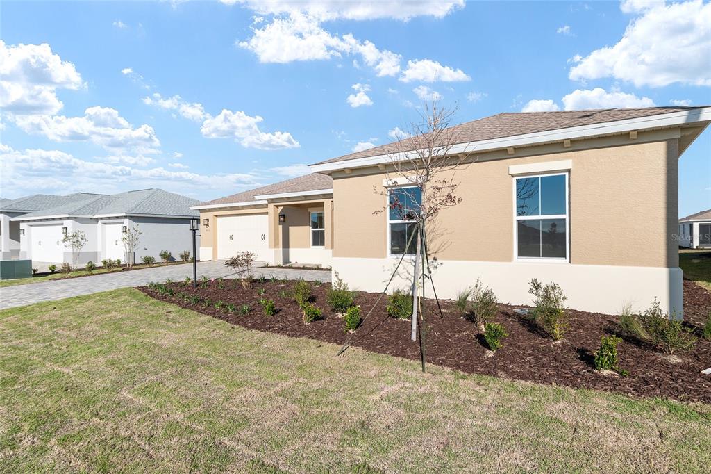 A tan single-story house with a two-car garage and a landscaped front yard — 8515 SW 101ST TERRACE, OCALA, FL