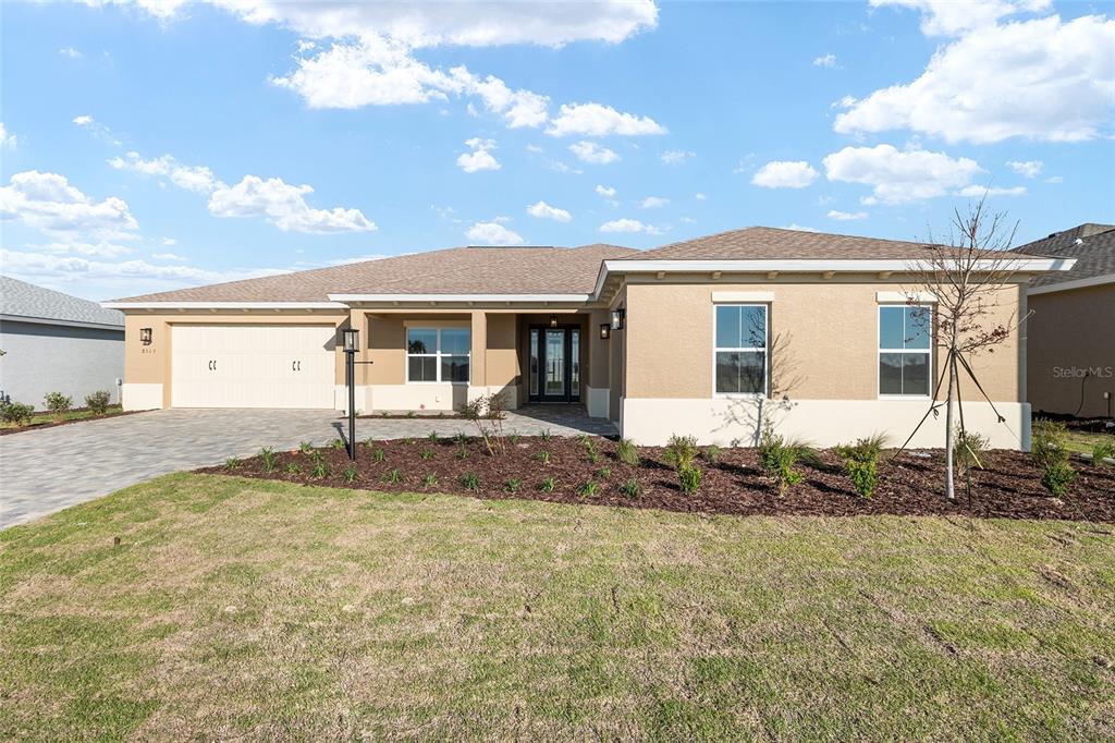 A single-story house with a beige stucco exterior, a paved driveway, and a two-car garage — 8515 SW 101ST TERRACE, OCALA, FL
