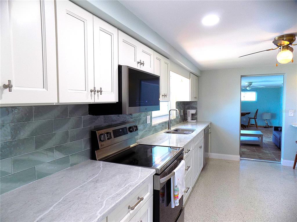 A kitchen features white cabinets, gray subway tile backsplash, and light-colored stone countertops — 3842 HEADSAIL DRIVE, NEW PORT RICHEY, FL
