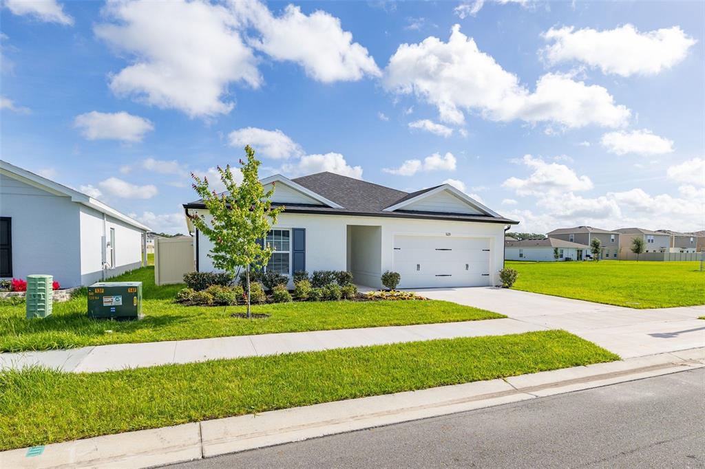 A single-story white house with a two-car garage and a green lawn — 1620 TEXAS AVENUE, SUMTERVILLE, FL