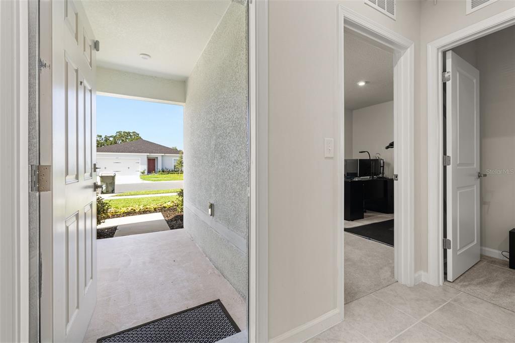 An open front door reveals a covered entryway and a view of a neighboring house — 1620 TEXAS AVENUE, SUMTERVILLE, FL
