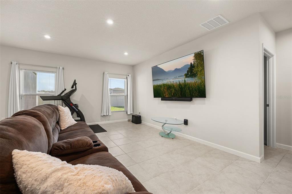 A living room with tile flooring, a wall-mounted television, and an exercise bike — 1620 TEXAS AVENUE, SUMTERVILLE, FL