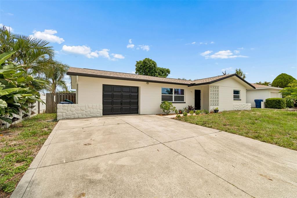 A single-story house with a white exterior, a black garage door, and a concrete driveway — 11555 63RD AVENUE, SEMINOLE, FL