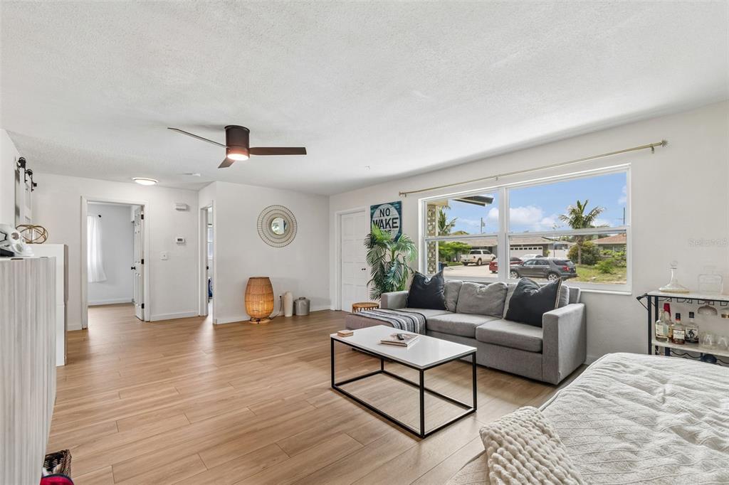 A living room features light wood-look flooring, a gray sofa, and a large window — 11555 63RD AVENUE, SEMINOLE, FL