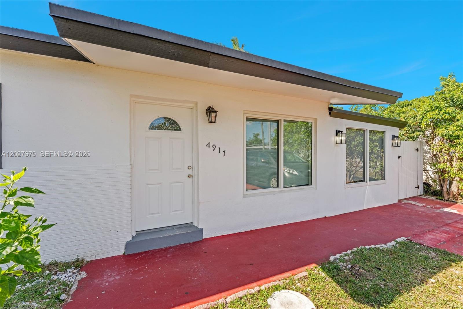 The exterior of a white house features a red walkway and a front door — 4917 SW 43rd Ter # A, Dania Beach FL 33314, DANIA BEACH, FL