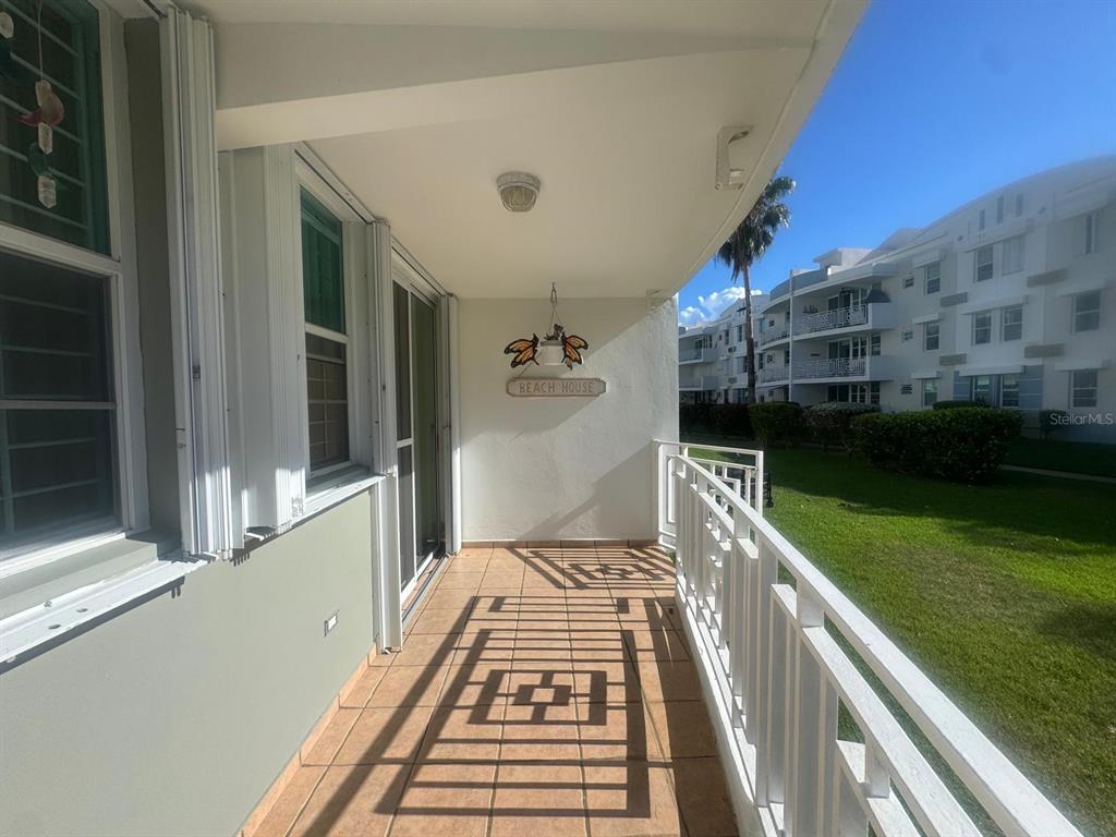 A covered balcony features tiled flooring, a white railing, and a view of neighboring buildings — II LOS PARILLAS UNIT 3501, LOIZA, PR